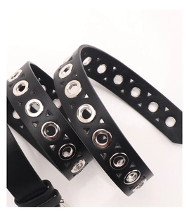 Detail of punk style black leather belt with silver eyelets and hollow triangle cutouts