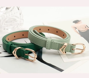 Dettaglio di sottili cinture in pelle con fibbie a V dorate nei colori verde e kaki