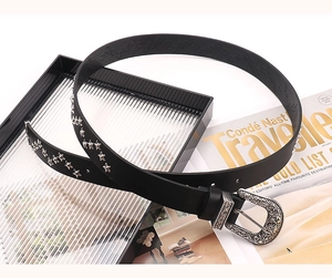Détail d'une ceinture punk avec rivets en étoile argentés et boucle à fleurs gravée