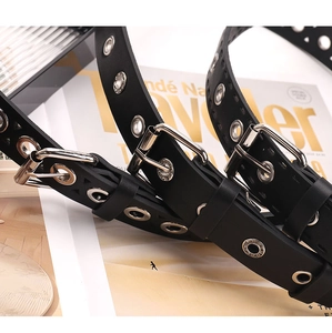 Close-up of black PU leather belt with silver hollow metal eyelets and a pin buckle