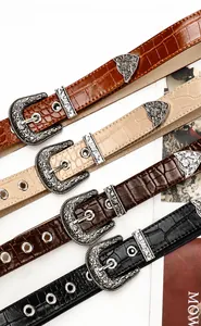 Detalle de cuatro cinturones de cuero vintage con hebillas grabadas y patrón de piedra