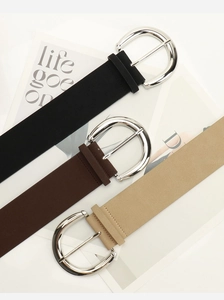 Close-up of vintage PU leather belts with large silver round buckles in multiple colors