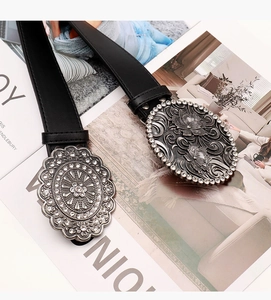 Detail of vintage black leather belts featuring silver engraved buckles with white rhinestones