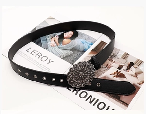 Close-up of vintage black leather belt with silver floral buckle and sparkling crystals