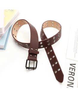 Detailed view of punk style dark brown leather belt with double silver metal eyelets