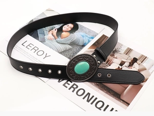 Detail of western retro black belt with turquoise oval buckle and embossed patterns