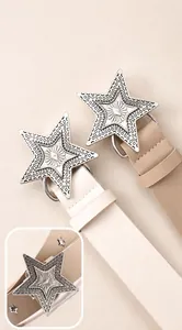 Detail of white and khaki belts featuring large star-shaped textured metal buckles