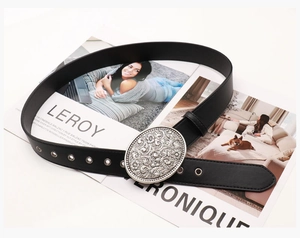 Detail of western black leather belt with engraved oval silver buckle on a magazine