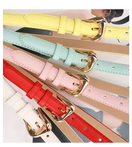 Detail of colorful slim waist belts with golden irregular metal buckles and fashion magazine