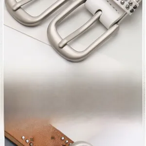 Close-up detail of leather belts with star punch holes and vintage metallic buckles