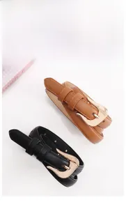 Detail view of thin leather belts in black and brown with polished gold buckle hooks