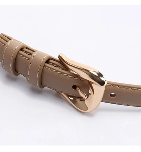Detail of khaki leather belt showing elegant rose gold irregular teardrop buckle