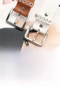 Detail of punk style brown and white belts with metal eyelets and silver square buckles