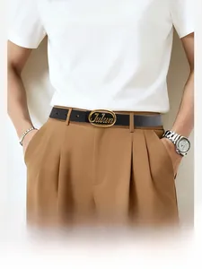 Detail of classic black leather belt with golden oval Julun buckle on brown trousers