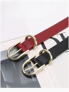 Detail of red and black leather belts with golden horseshoe buckles for women