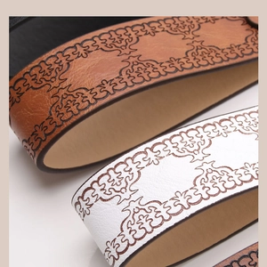 Close-up of vintage brown and white leather belts with intricate embossed floral patterns
