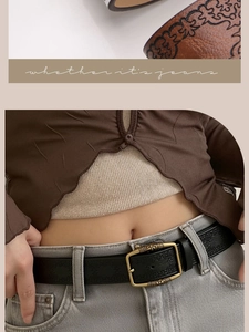 Detail of vintage bronze buckle and embossed floral pattern on black leather belt