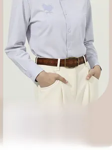 Detail of vintage brown leather belt with bronze buckle on casual trousers