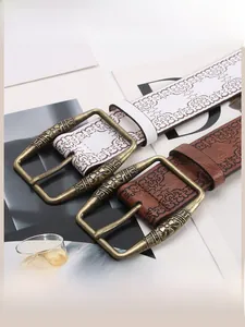 Detailed close-up of a vintage embossed leather belt with an ornate bronze alloy buckle