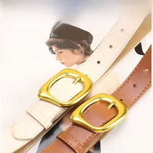 Detail view of cream and caramel leather belts with large square gold buckles for women