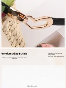 Détail de la boucle en alliage doré en forme de cœur sur une fine ceinture noire réglable