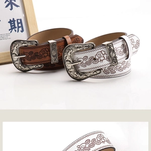 Close-up of vintage embossed leather belts with ornate silver floral metal buckles