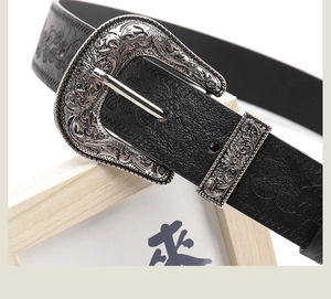 Detailed macro of vintage western belt buckle with floral embossed black leather texture