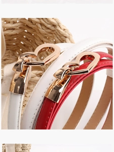 Détail de fines ceintures rouges et blanches avec boucles de cœur dorées en panier