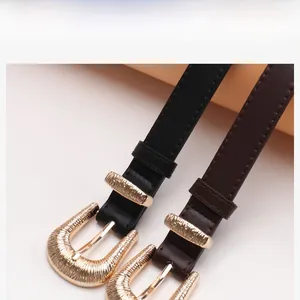Close-up of vintage gold alloy buckles with vertical stripes on thin leather belts