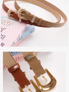 Detail of vintage skinny belts with engraved gold buckles in tan and caramel leather
