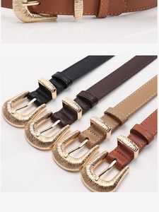 Close-up of four slim leather belts with vintage gold striped metal buckles in various colors