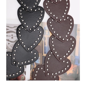 Macro detail of heart-shaped leather belt with silver rivets and lychee texture