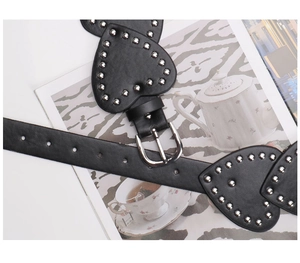 Close-up of black leather heart belt with silver rivets and metal buckle detailing