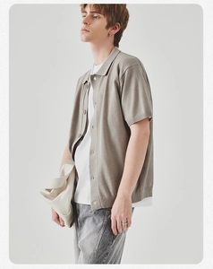Dettaglio di un cardigan polo in maglia grigio chiaro da uomo con borsa in pelle crema