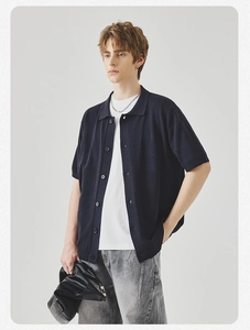 Dettaglio del cardigan polo in maglia blu scuro con maglietta bianca e jeans grigi