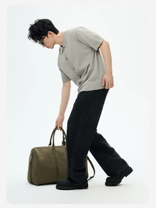 Polo uomo in maglia grigio chiaro con borsa da viaggio oliva e stivali neri alla moda