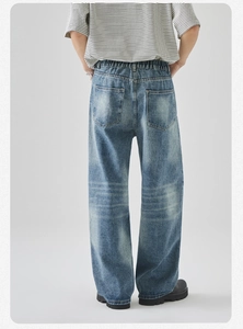 Dettaglio dei jeans in denim blu lavato vintage con texture usurata e vestibilità ampia