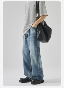 Dettaglio di jeans a gamba larga lavati vintage con t-shirt a righe e borsa a tracolla