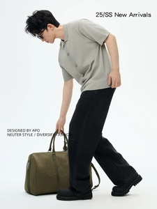 Polo da uomo in maglia verde salvia con jeans neri larghi e borsa da viaggio in tela verde