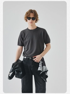 T-shirt in maglia grigia da uomo con jeans neri e accessori in pelle coordinati
