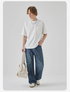 Full model shot of white cotton t-shirt with pocket and oversized ripped blue jeans