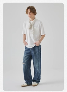 Detail of men's white pocket T-shirt with striped shawl and ripped blue wide-leg jeans