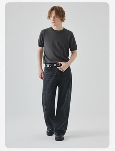 Dettaglio di una maglietta in maglia grigio scuro aderente con jeans neri e cintura in pelle
