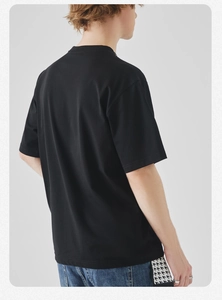 Rear view of a black crew neck T-shirt with blue jeans featuring houndstooth patchwork details