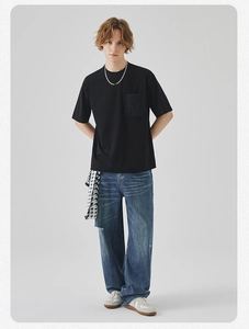 Close-up of black cotton T-shirt with chest pocket and silver chain necklace detail