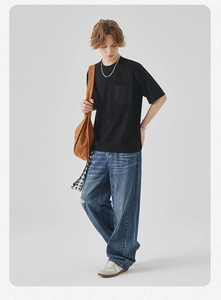 Detail of black cotton T-shirt with chest pocket and relaxed fit light blue denim jeans