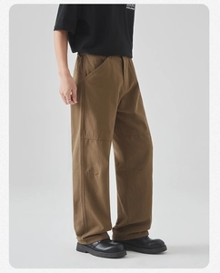 Detail of loose fit brown cotton utility pants showing fabric texture and pocket design