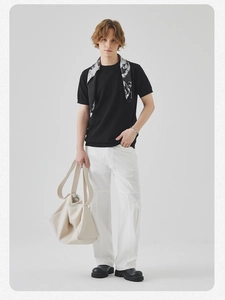 Dettaglio di maglietta nera a maglia con borsa tote in pelle bianca dallo stile moderno