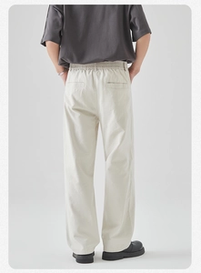 Detail view of men's beige straight-leg trousers with elastic waistband and back pockets