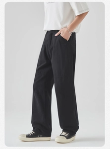 Detail view of black cotton cargo pants with knee seam stitching and loose straight fit